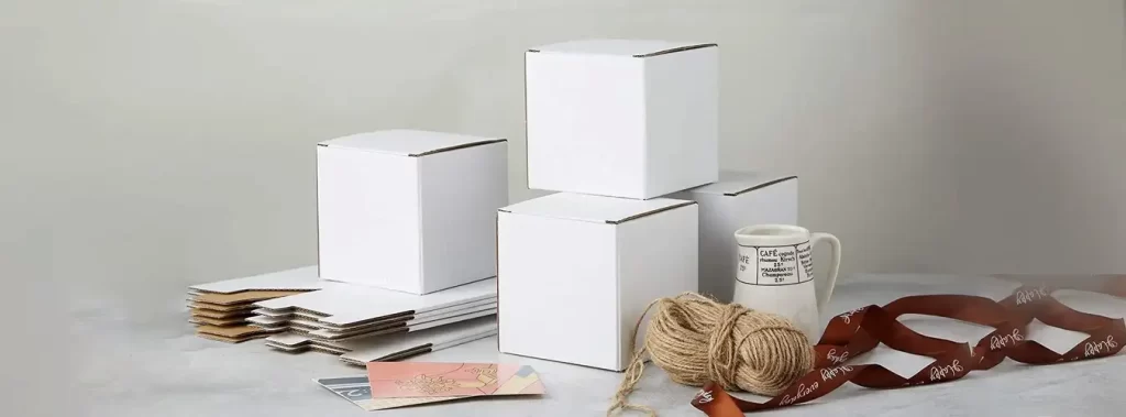 A collection of white boxes made of paperboard and cardboard arranged on a table with additional items