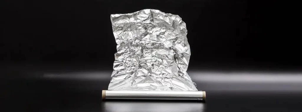 An artistic silver foil sculpture positioned on a black background, emphasizing the innovative design of aluminum packaging